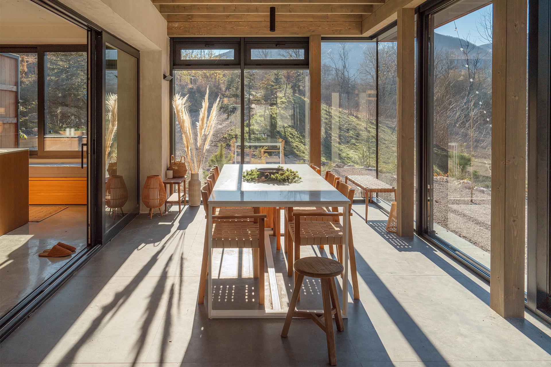 Essbereich mit großen Panoramafenstern und Blick auf die Natur.
